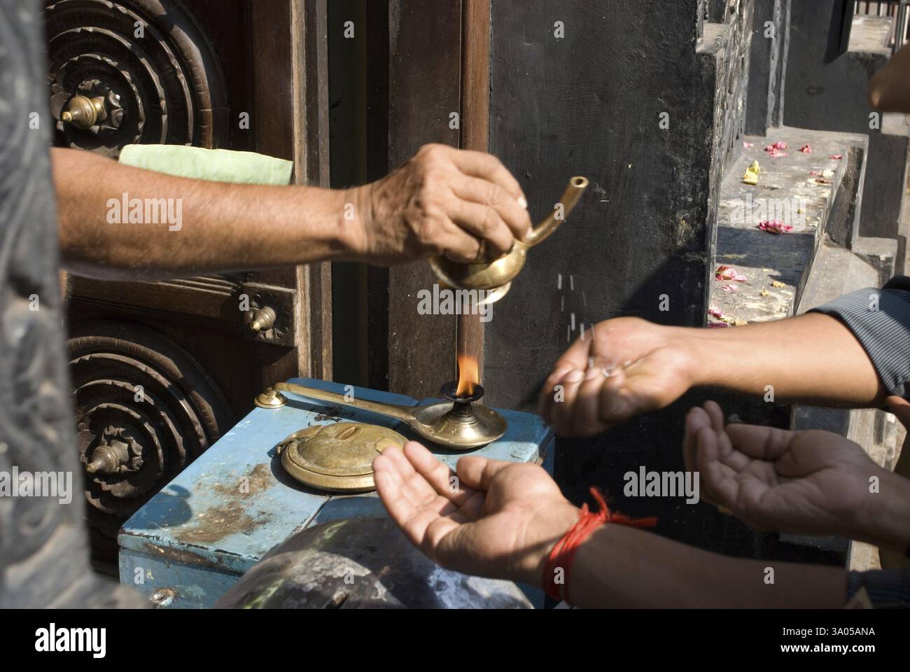 Sacerdote che versa charnaamrita sulle mani dei devoti, Trivandram, Kerala, India, Asia Foto Stock