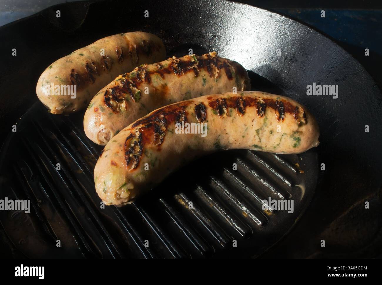 Processo di cottura: Salsiccia di maiale fritta su una padella di ghisa Foto Stock