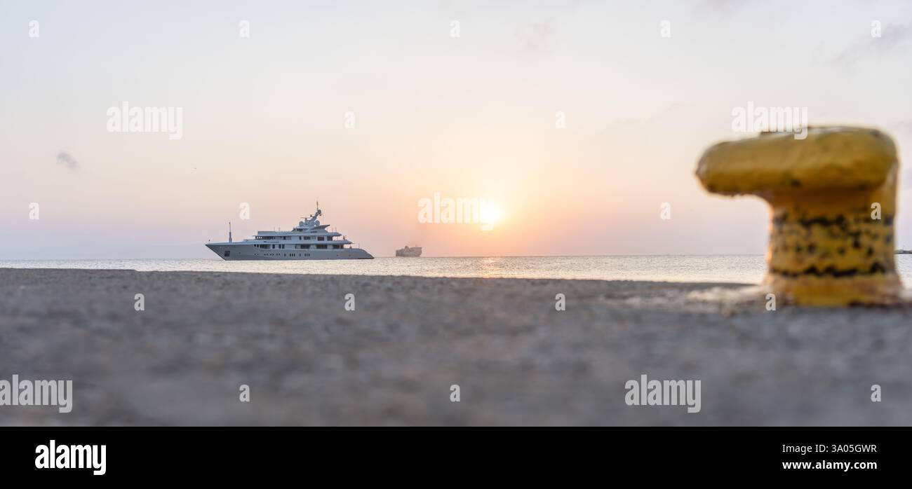 Barca di lusso ormeggiata al molo sulla costa di Kos con Blue Star Ferry sullo sfondo e dissuasore giallo in primo piano Foto Stock