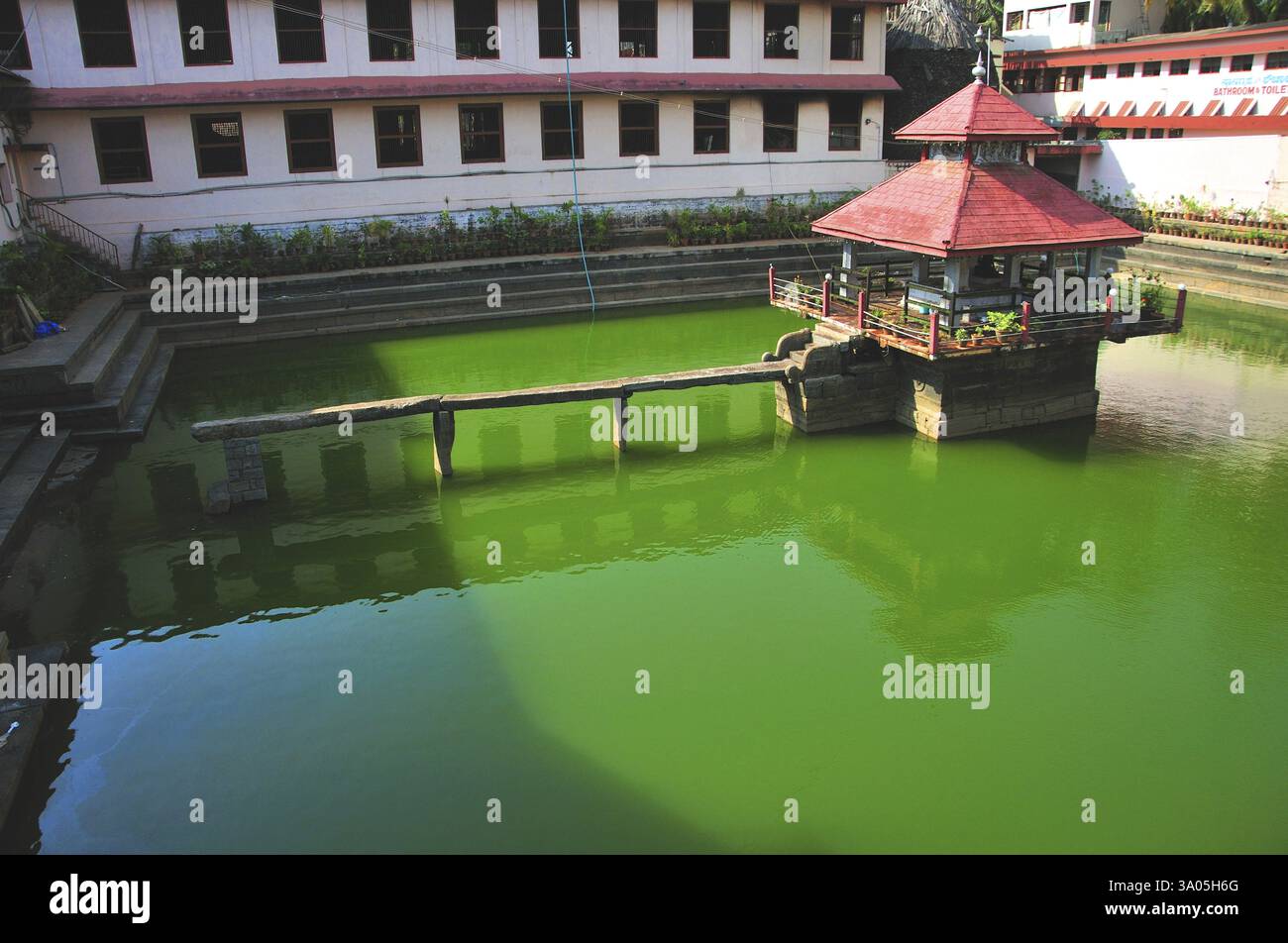 Tempio al centro dello stagno e ponte composto da lastra di pietra a ShriKrishna Math, Udipi, Karnataka, India, 5 maggio 2009 Foto Stock