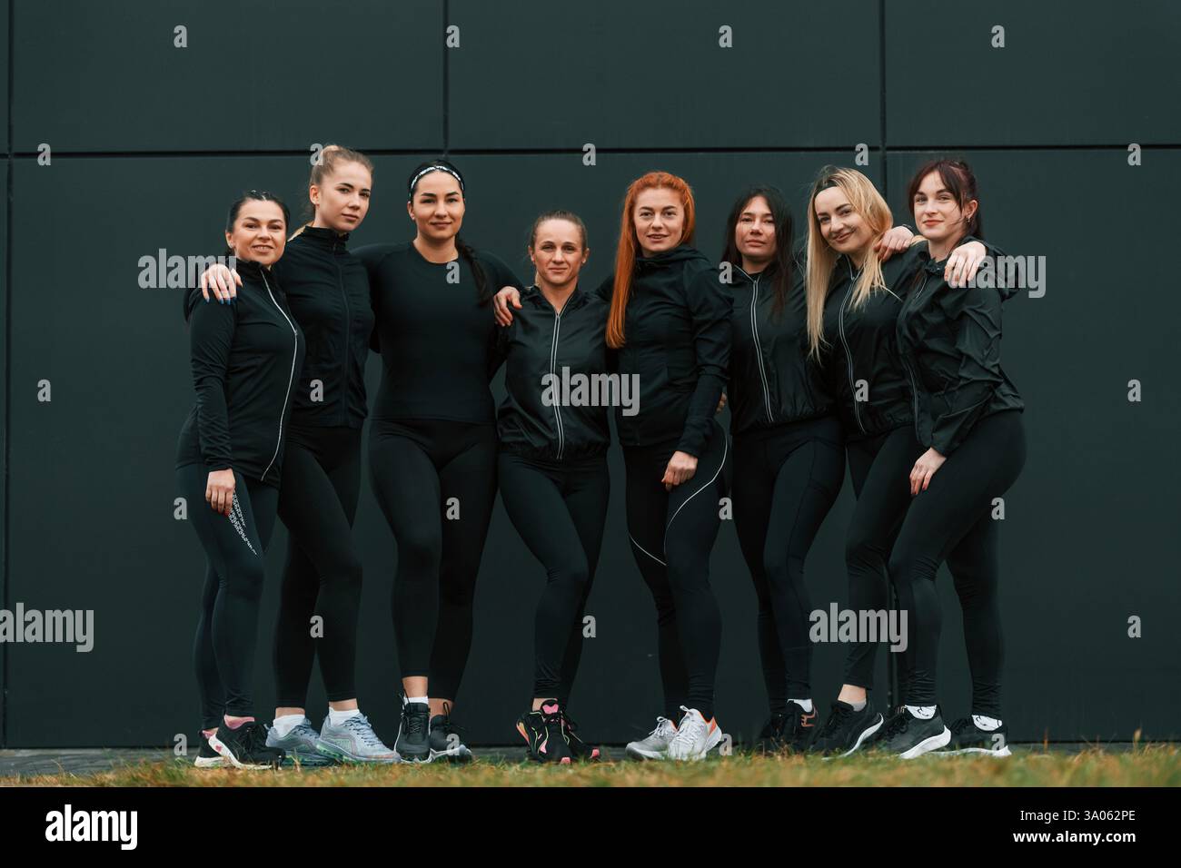 In piedi e in posa. Un gruppo di donne sportive si trova all'aperto vicino all'edificio nero. Foto Stock
