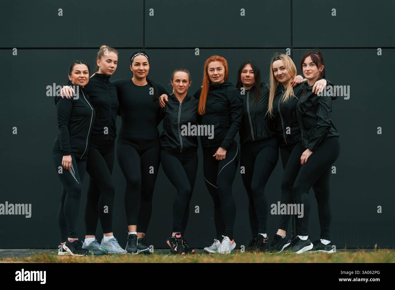 In piedi e in posa. Un gruppo di donne sportive si trova all'aperto vicino all'edificio nero. Foto Stock