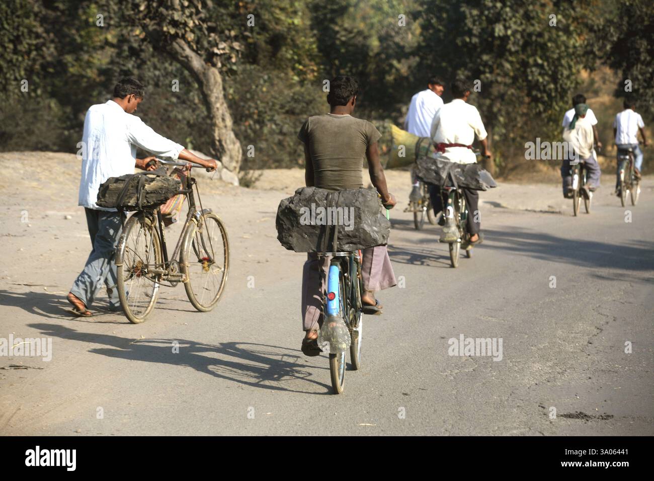 Lavoratori della miniera di carbone che trasportano un pezzo di carbone caricato sul sedile posteriore di biciclette a Jharkhand, India, Asia Foto Stock