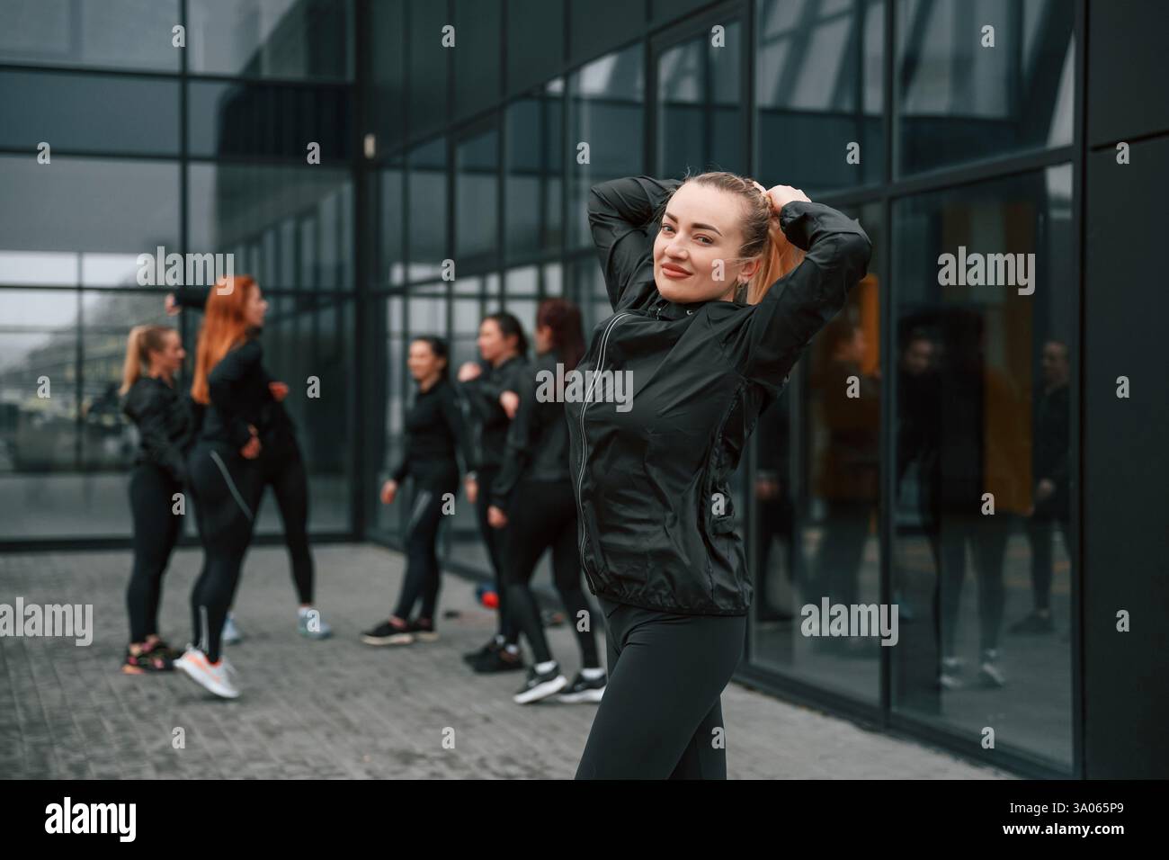 Un gruppo di donne sportive si trova all'aperto vicino all'edificio nero. Foto Stock