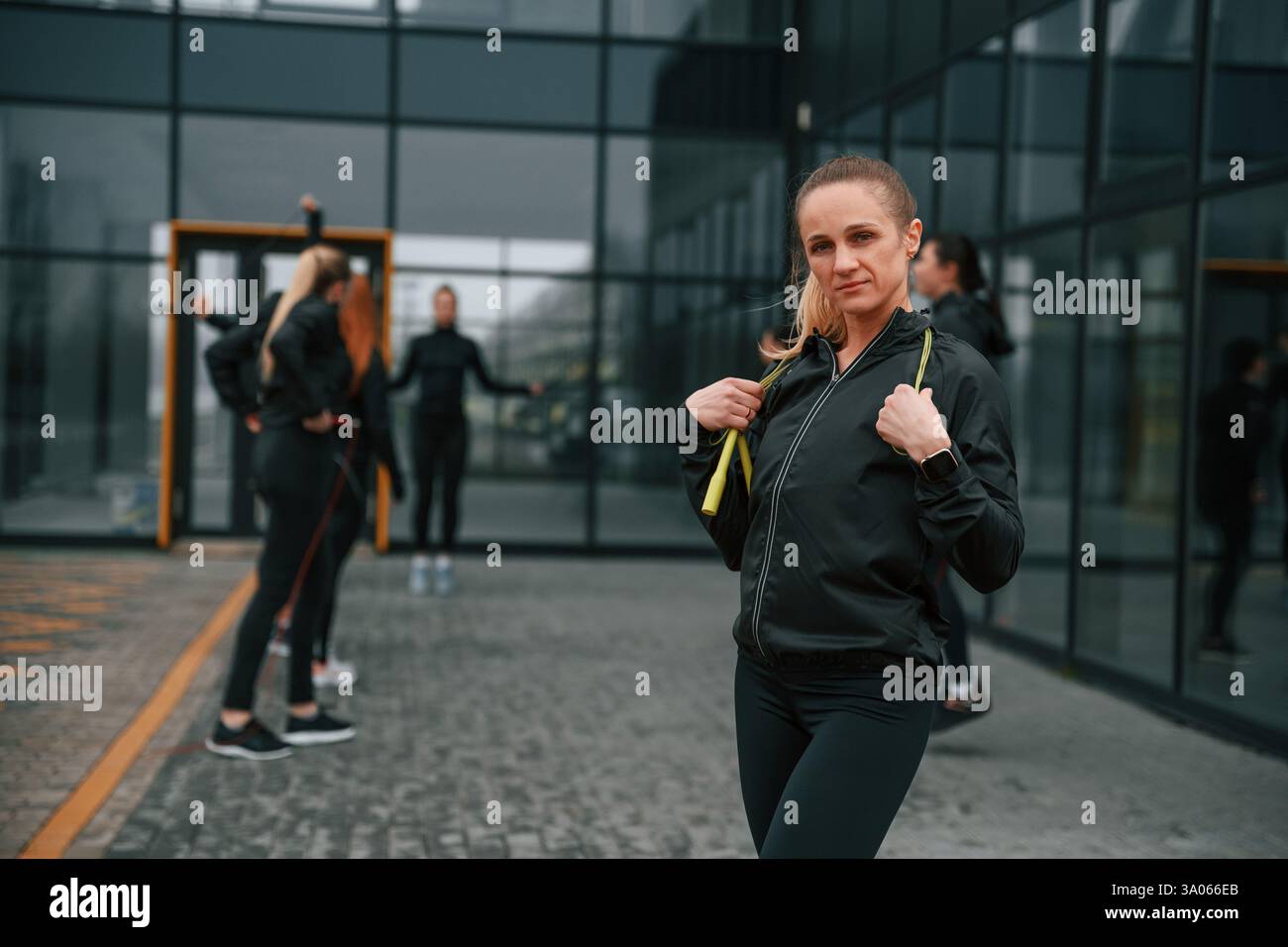 Un gruppo di donne sportive si trova all'aperto vicino all'edificio nero. Foto Stock