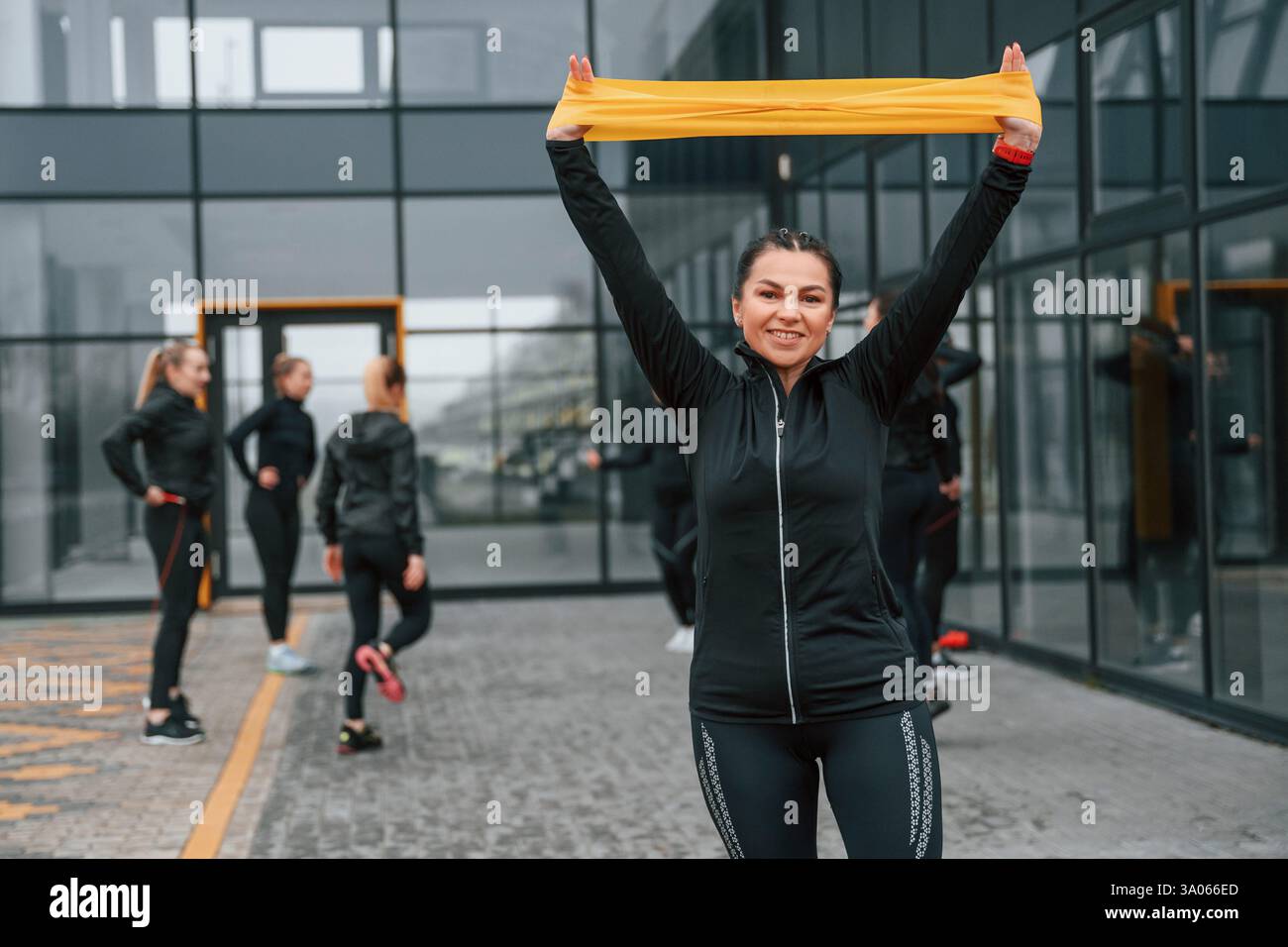 Espansore di tenuta. Un gruppo di donne sportive si trova all'aperto vicino all'edificio nero. Foto Stock