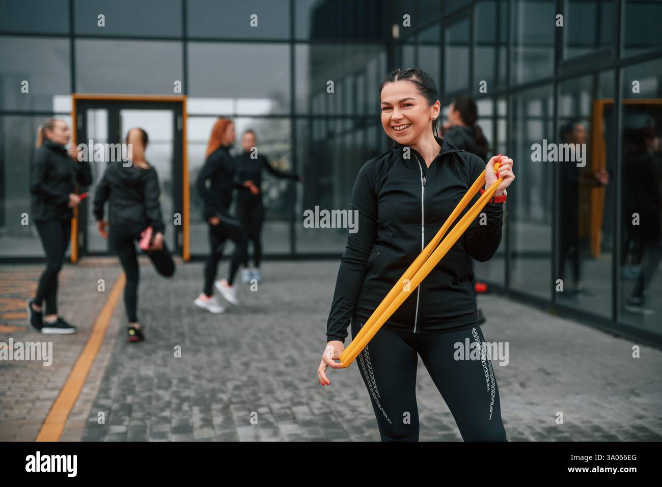 Espansore di tenuta. Un gruppo di donne sportive si trova all'aperto vicino all'edificio nero. Foto Stock