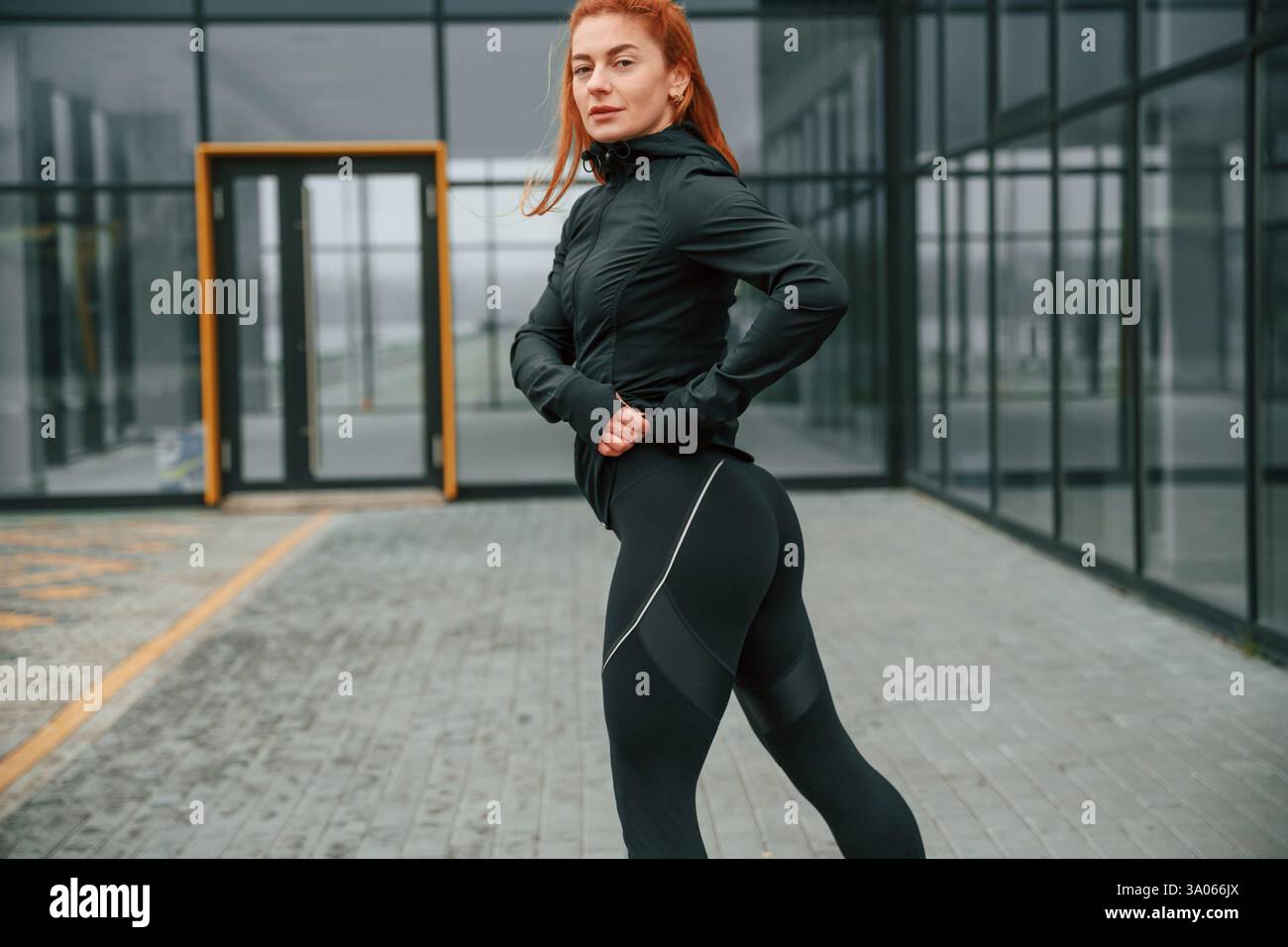 La donna è abbigliamento sportivo all'aperto contro l'edificio nero. Foto Stock