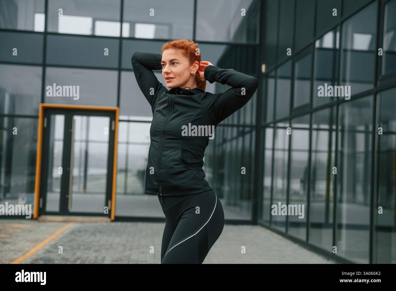 La donna è abbigliamento sportivo all'aperto contro l'edificio nero. Foto Stock