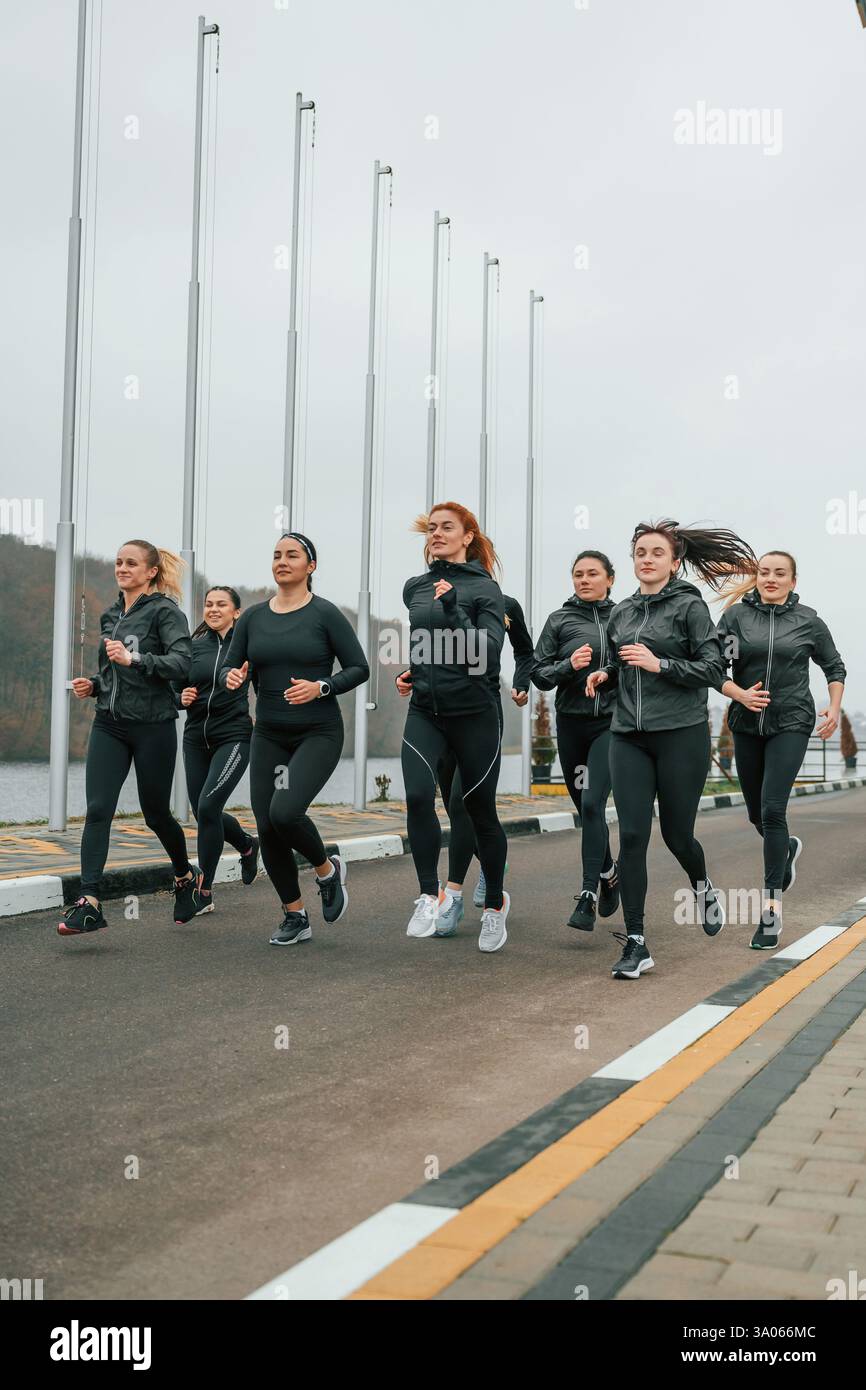 Correndo insieme. Un gruppo di donne sportive si trova all'aperto vicino all'edificio nero. Foto Stock