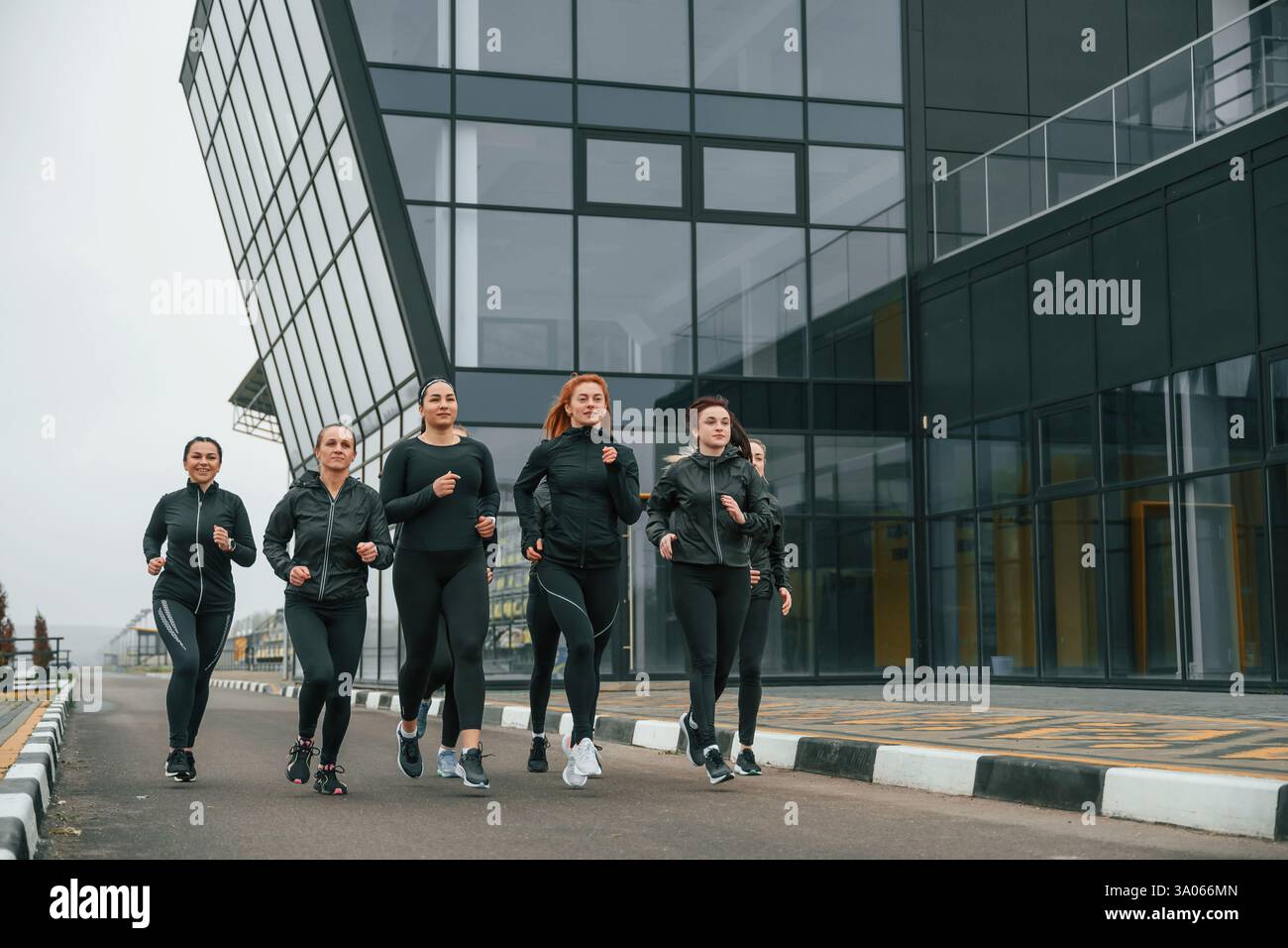 Correndo insieme. Un gruppo di donne sportive si trova all'aperto vicino all'edificio nero. Foto Stock