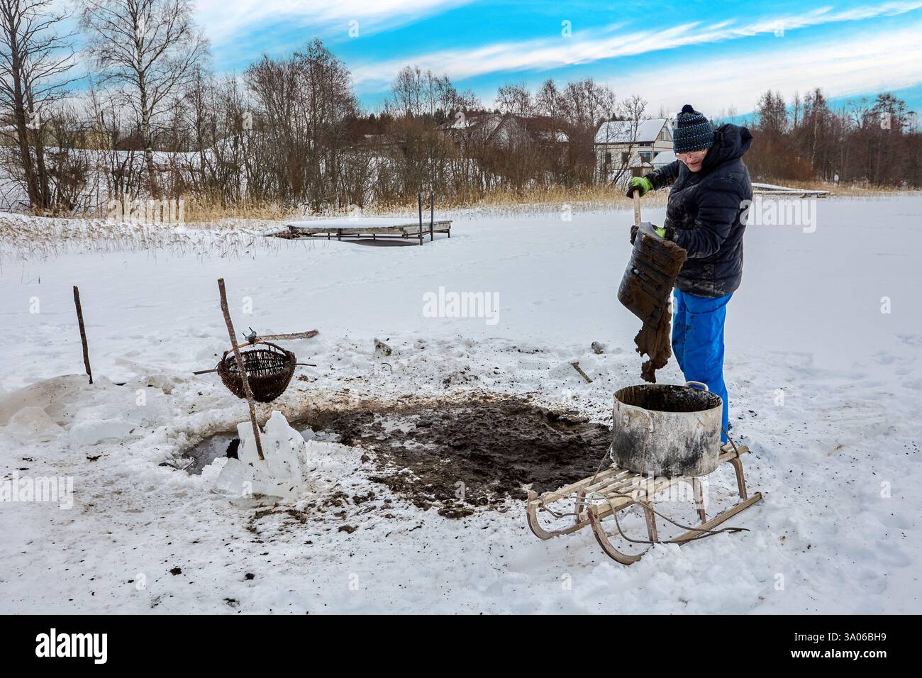 L'inverno trova contadini che estraggono la sapropel dalla fonte di acqua dolce, il muck viene sollevato attraverso il foro, caricato dalla pala, tirato sulla slitta per la fertilizzazione. Foto Stock