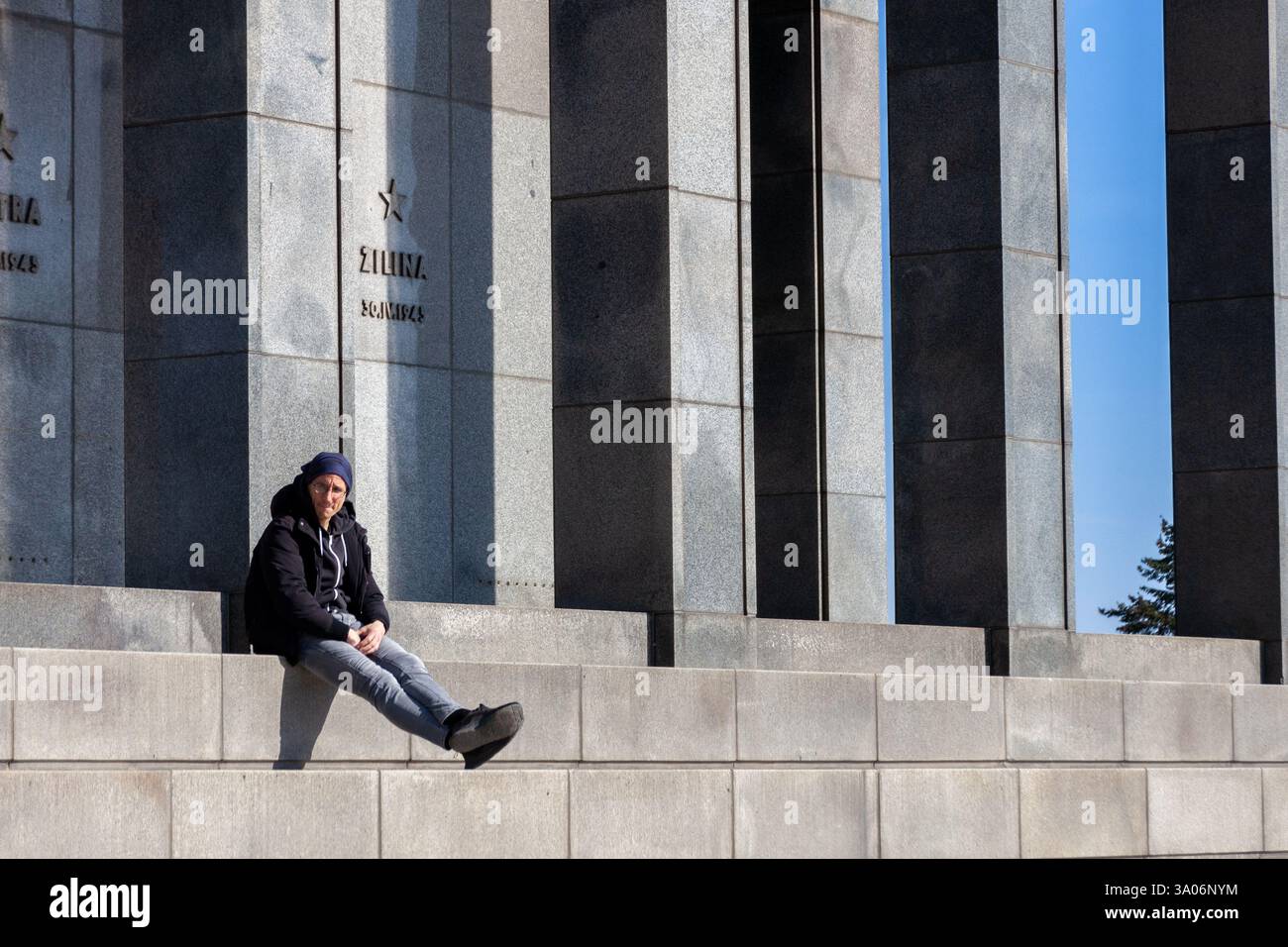 Un giovane solitario che si rilassa accanto al Monumento di Slavín in una giornata di sole. Bratislava, Slovacchia. Foto Stock