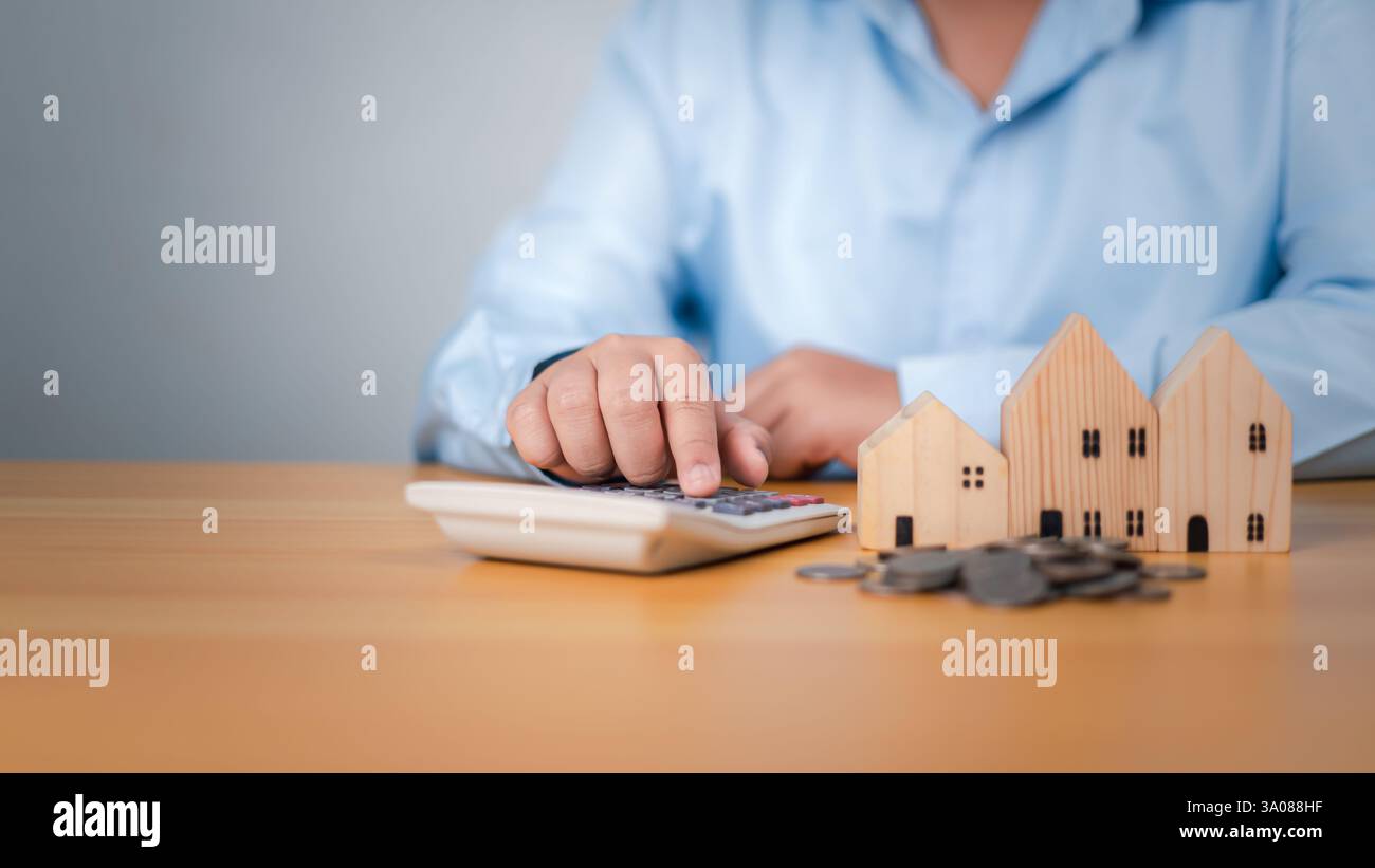 Casa con soldi, premendo una calcolatrice accanto a un modello di casa e monete, concetto di finanza o rifinanziamento immobiliare, flusso di cassa immobiliare, risparmio di denaro Foto Stock