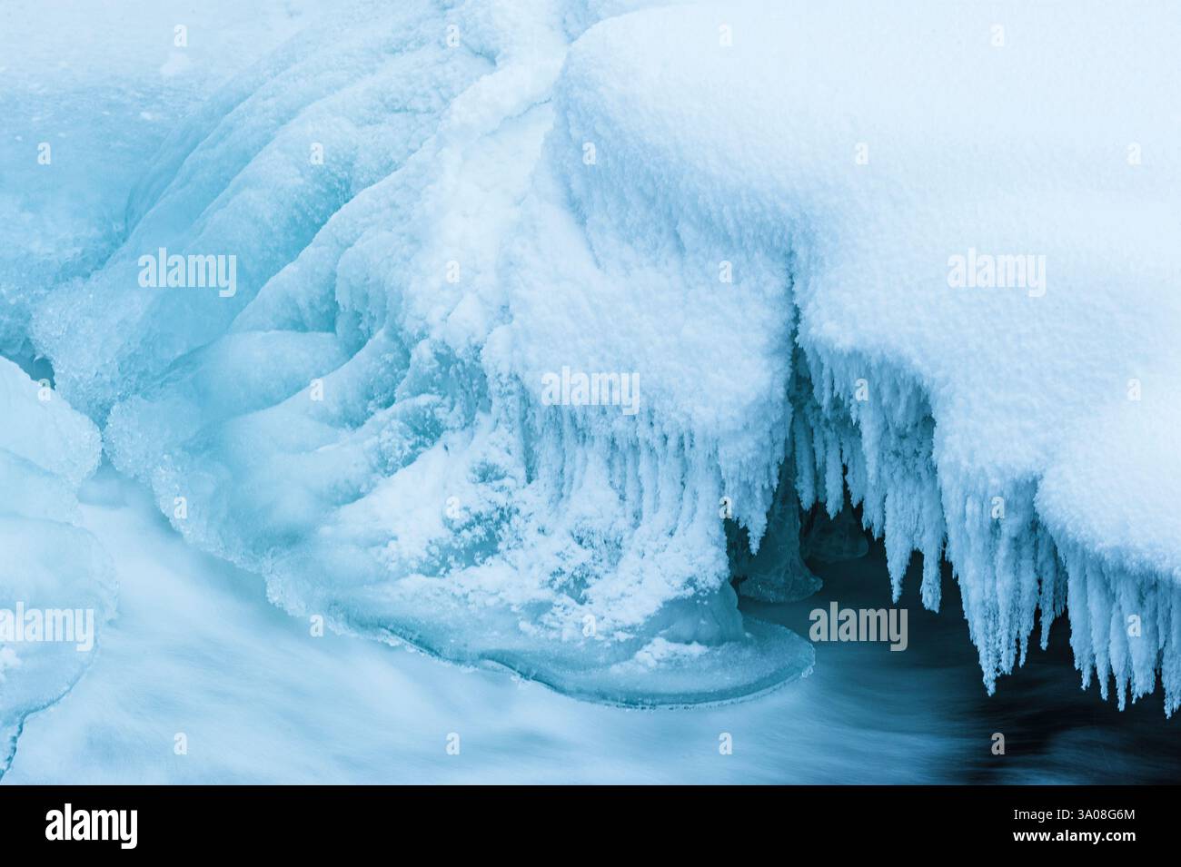 Le fredde acque di un fiume in Svezia scorrono dolcemente, circondate da impressionanti formazioni di ghiaccio e sponde ghiacciate. L'inverno ha trasformato il paesaggio in un Foto Stock