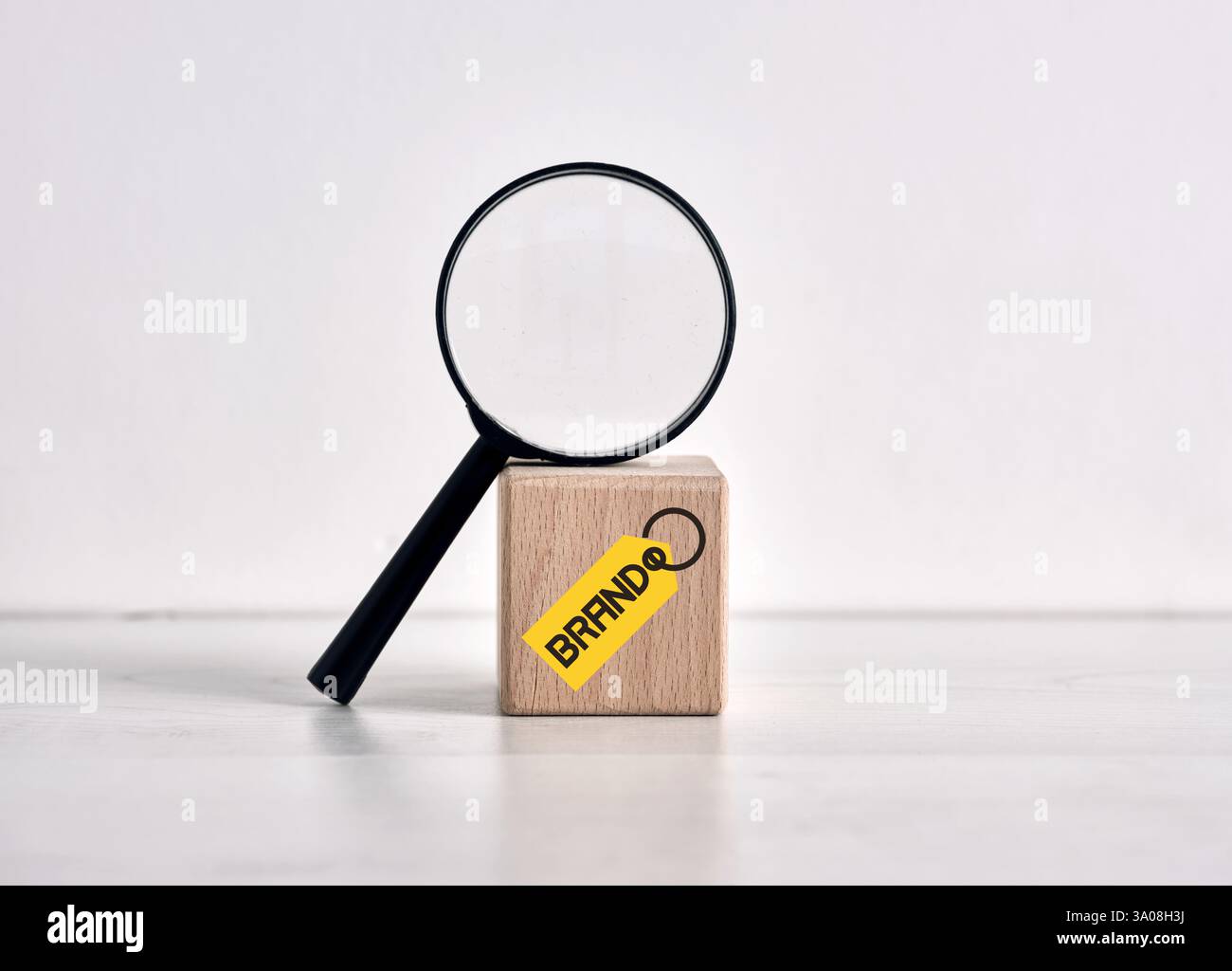 Lente d'ingrandimento che ispeziona la reputazione del marchio su un cubo di legno con etichetta gialla, concetto di gestione della reputazione del marchio e analisi dei marchi Foto Stock