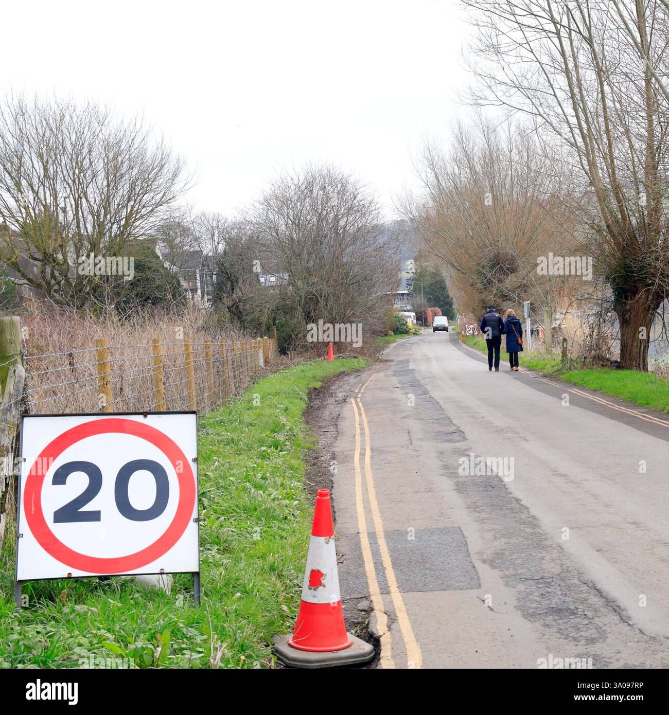 Cartello con limite di velocità di 20 km/h e coppia che cammina su Mead Lane, Saltford vicino a Bristol. Preso nel gennaio 2025. Inverno Foto Stock