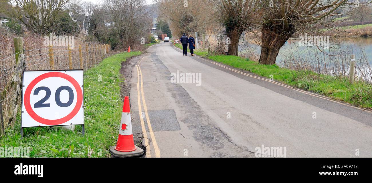 Cartello con limite di velocità di 20 km/h e coppia che cammina su Mead Lane, Saltford vicino a Bristol. Preso nel gennaio 2025. Inverno Foto Stock