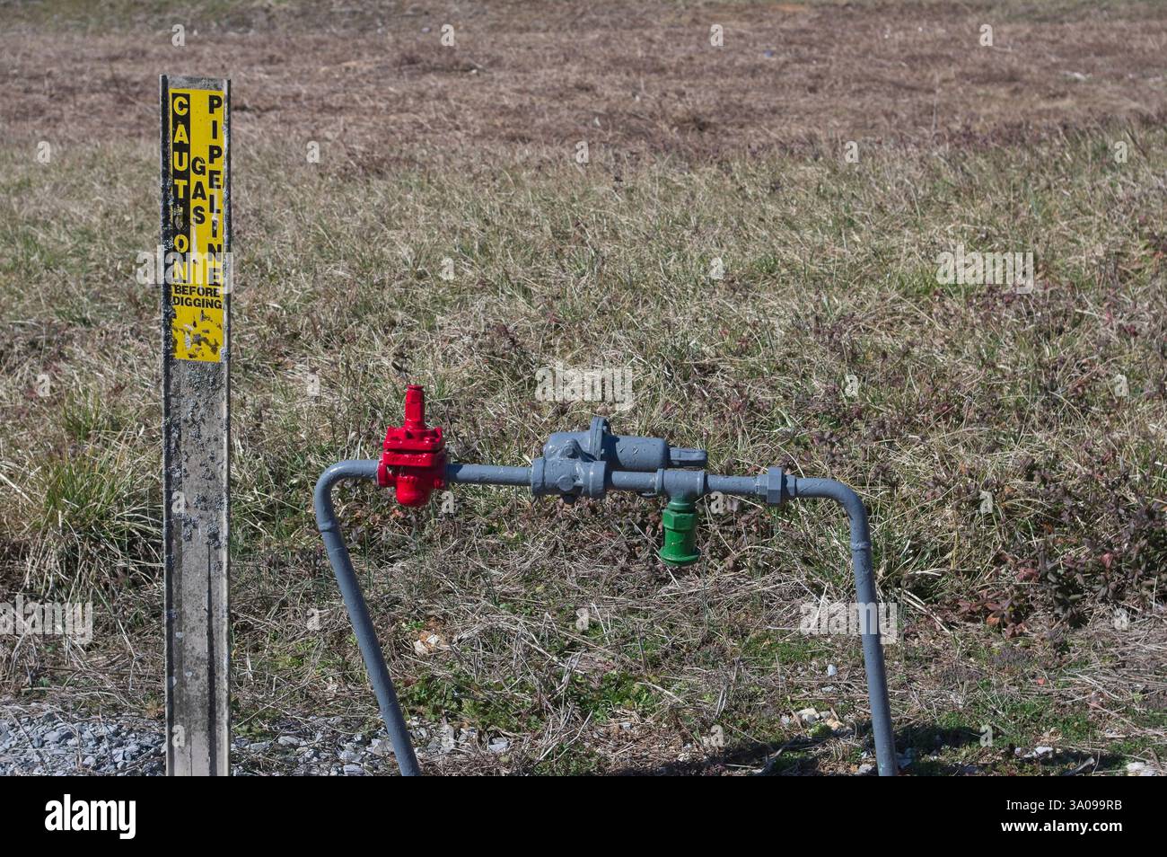Valvola della tubazione del gas appena verniciata e palo di attenzione Foto Stock
