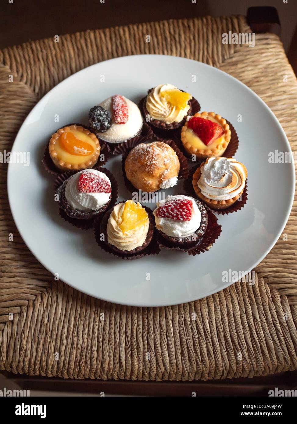 Nove dolci italiani in piatto bianco su Straw Chair Foto Stock
