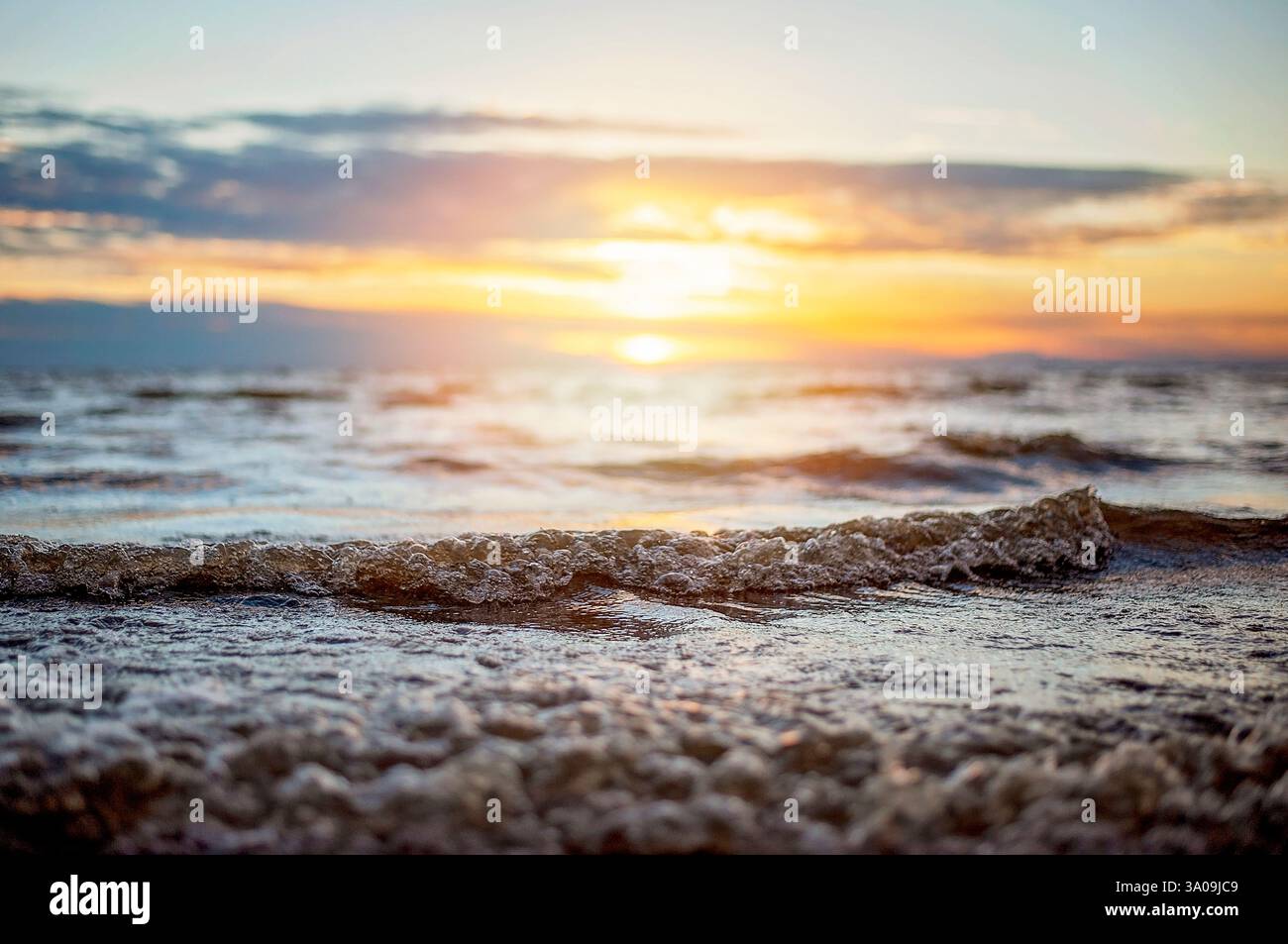 Primo piano delle onde dell'oceano al tramonto con riflessi dorati sull'acqua Foto Stock