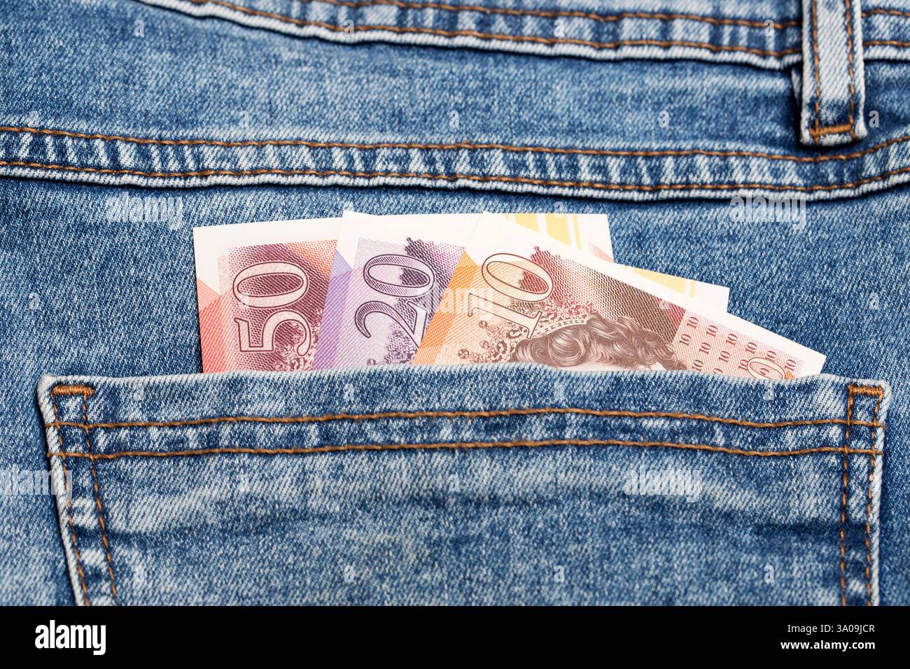 Soldi inglesi - sterlina nella tasca dei jeans blu Foto Stock