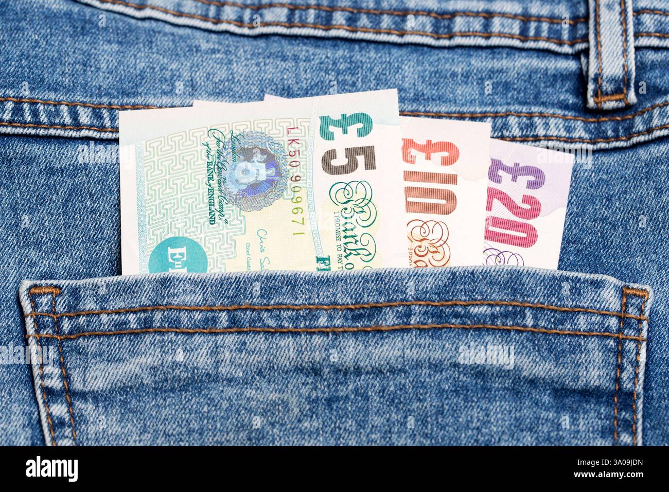 Soldi inglesi - sterlina nella tasca dei jeans blu Foto Stock