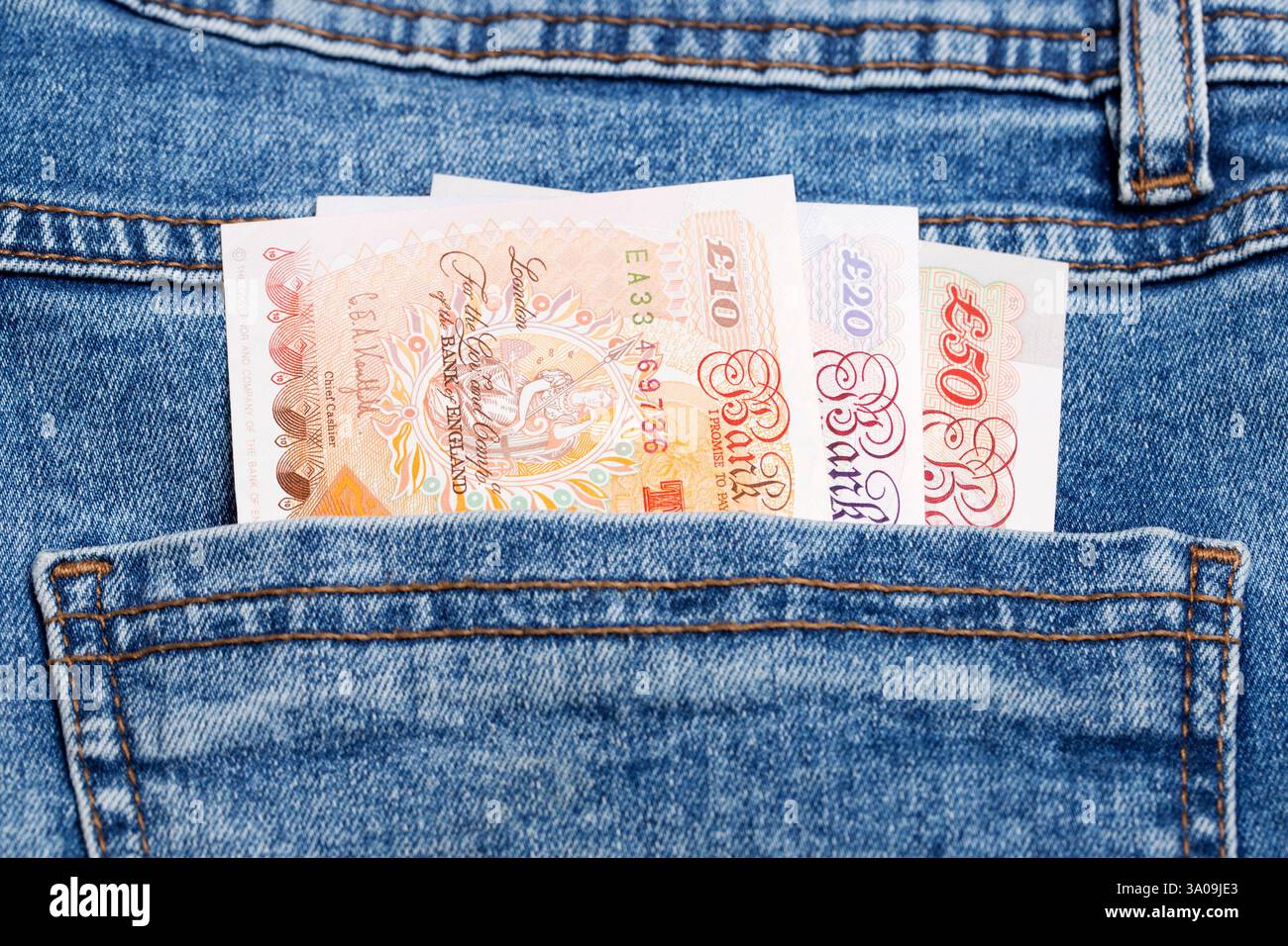 Soldi inglesi - sterlina nella tasca dei jeans blu Foto Stock