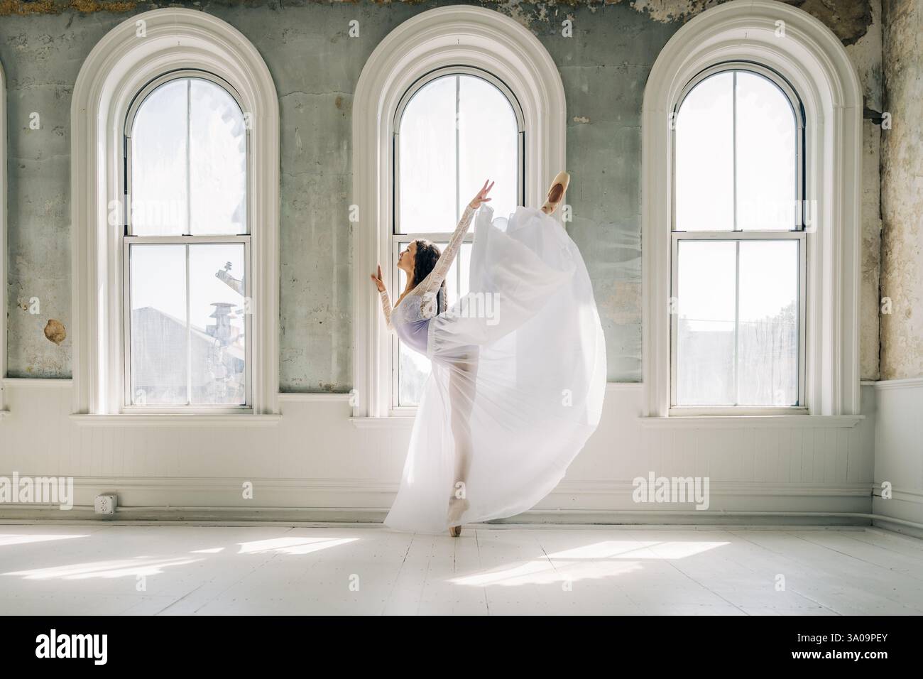 Ballerina di balletto in un abito bianco che scorre esegue un grazioso arabesco Foto Stock