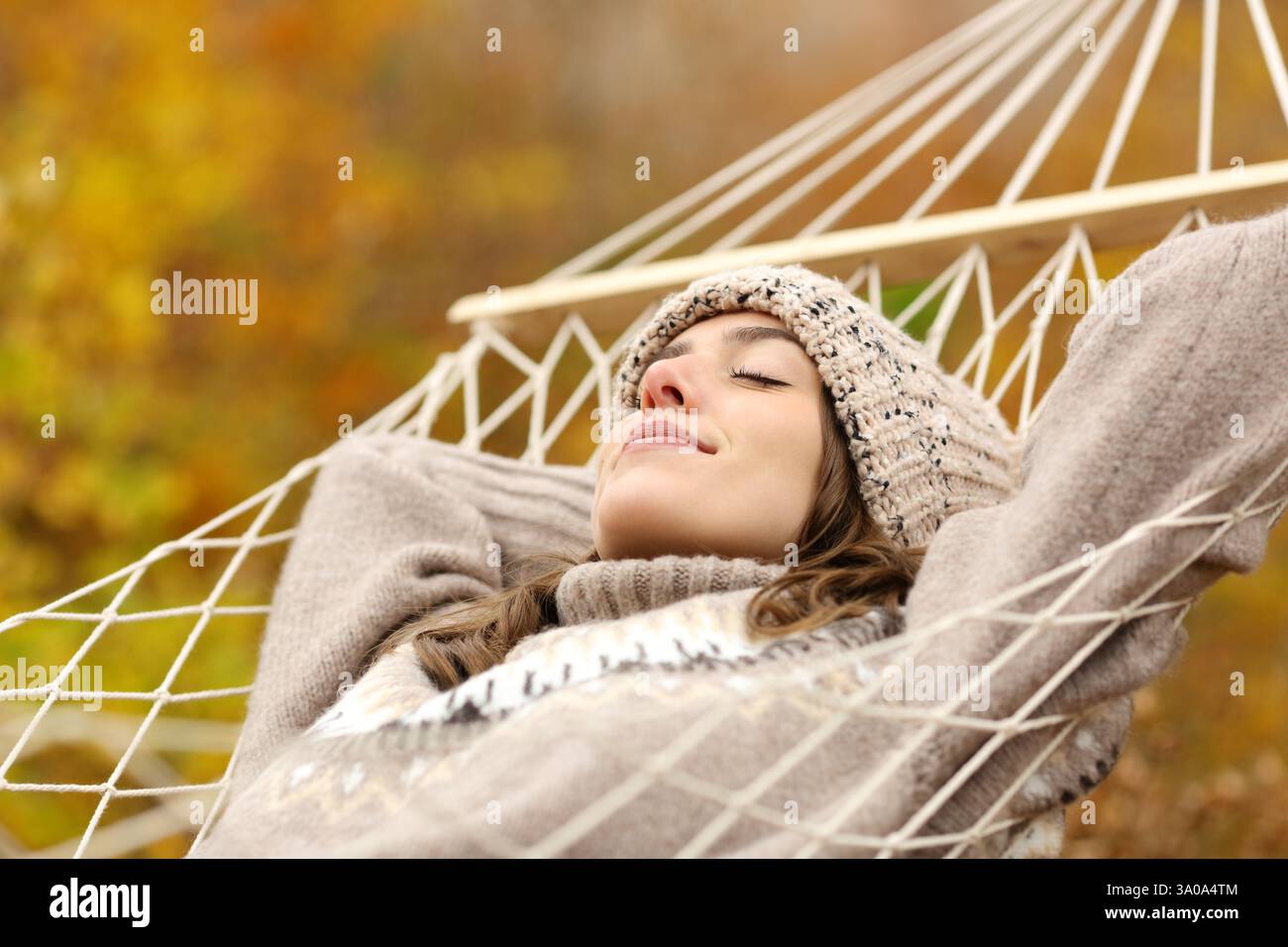 Donna rilassata che dorme sdraiata su un'amaca in natura in inverno Foto Stock