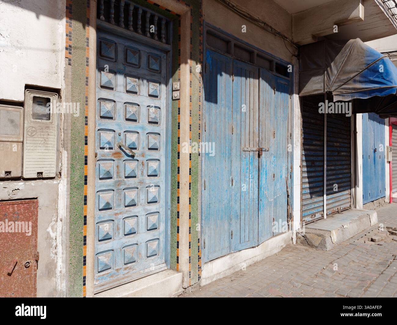 Fatiscente corso lungo la strada con porte blu a Essaouira, in Marocco. 2 marzo 2025 Foto Stock