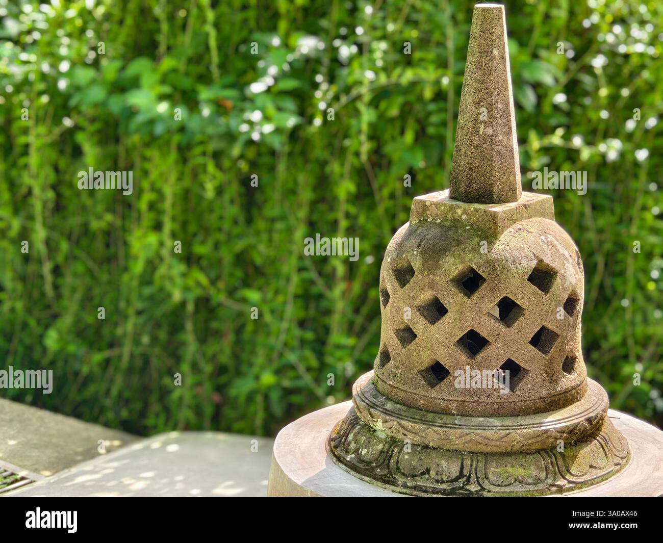 Tabanan, Bali, Indonesia - 1 marzo 2025: Stupa decorativo in pietra scolpita in miniatura in un giardino di architettura buddista Foto Stock