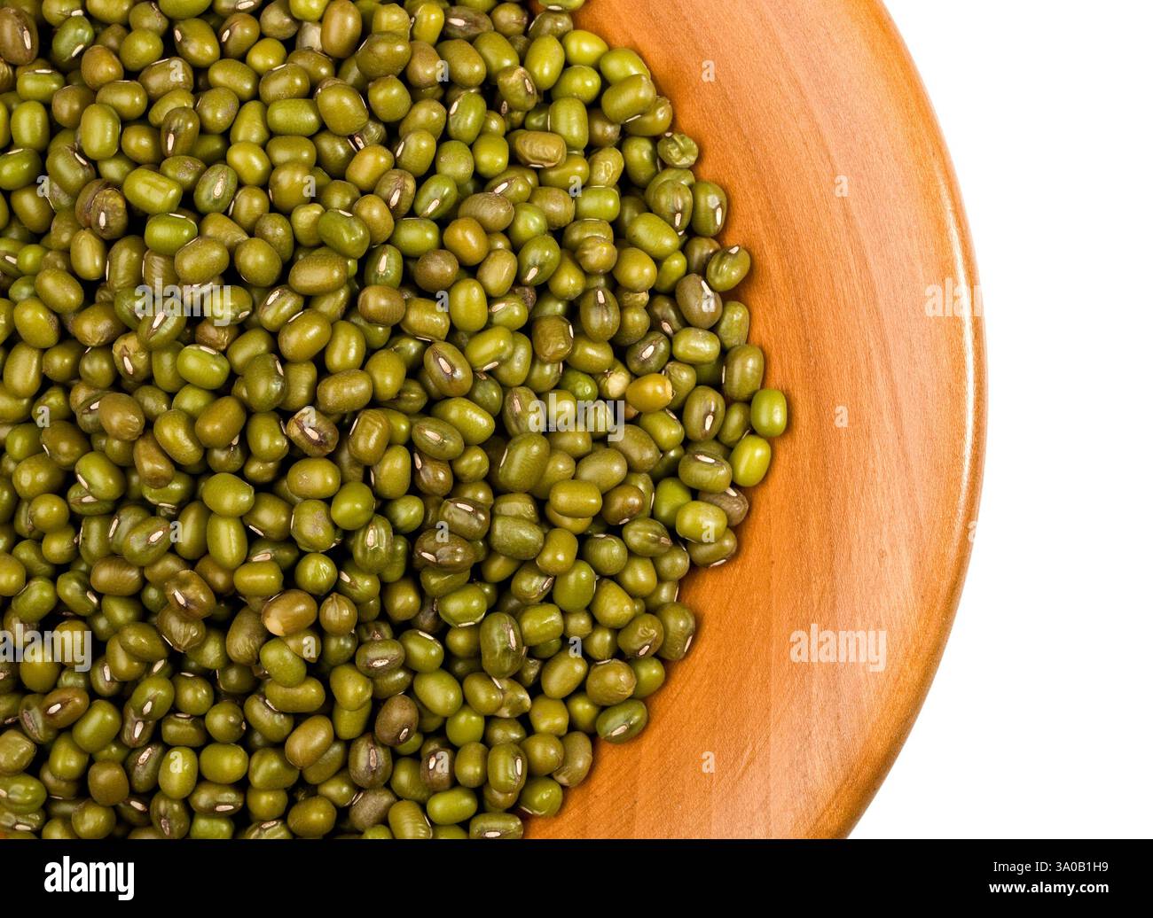 Primo piano di fagioli mung che traboccano di una ciotola di legno, mostrando la loro bellezza naturale e il loro valore nutrizionale Foto Stock