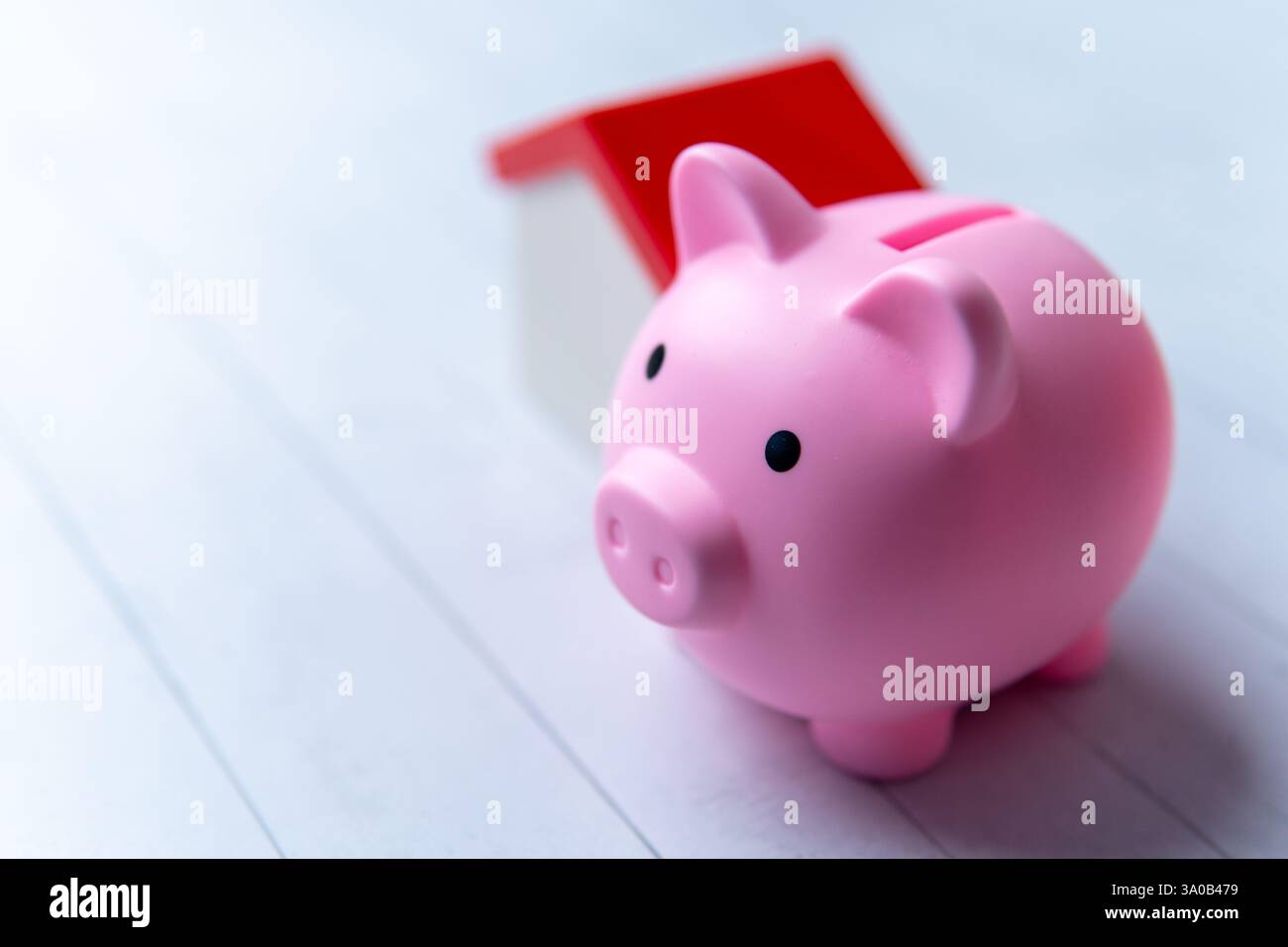 Un salvadanaio rosa e una casa dei giocattoli. Risparmio per un concetto di casa o di mutuo. Copia spazio per il testo. Foto Stock