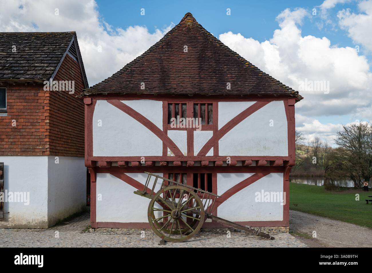 Vecchio edificio all'interno del museo vivente di Weald and Downland con un vecchio carro di legno sul lastricato all'esterno. Febbraio 2025. Foto Stock