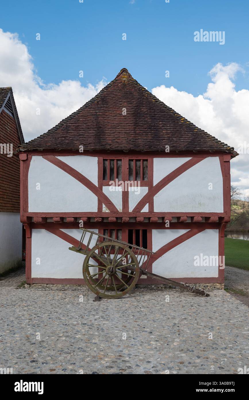 Vecchio edificio all'interno del museo vivente di Weald and Downland con un vecchio carro di legno sul lastricato all'esterno. Febbraio 2025. Foto Stock