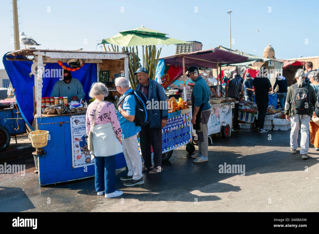 Essaouira, Marocco - 17 febbraio 2025: I visitatori esplorano bancarelle colorate piene di prodotti locali e prodotti freschi a Essaouira. Foto Stock