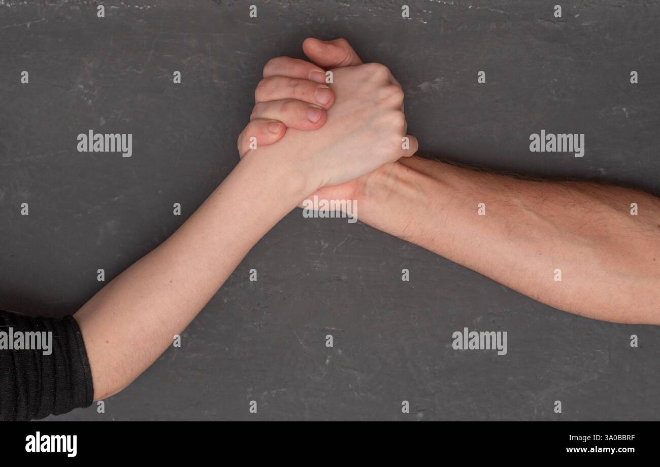 braccia da uomo e da donna su sfondo grigio Foto Stock