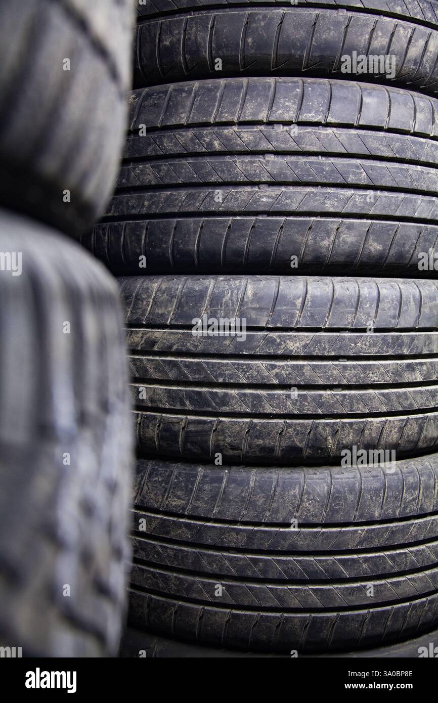 Magazzino di automobili con stoccaggio errato di pneumatici per auto in una pila, sfondo con ruote ordinate Foto Stock