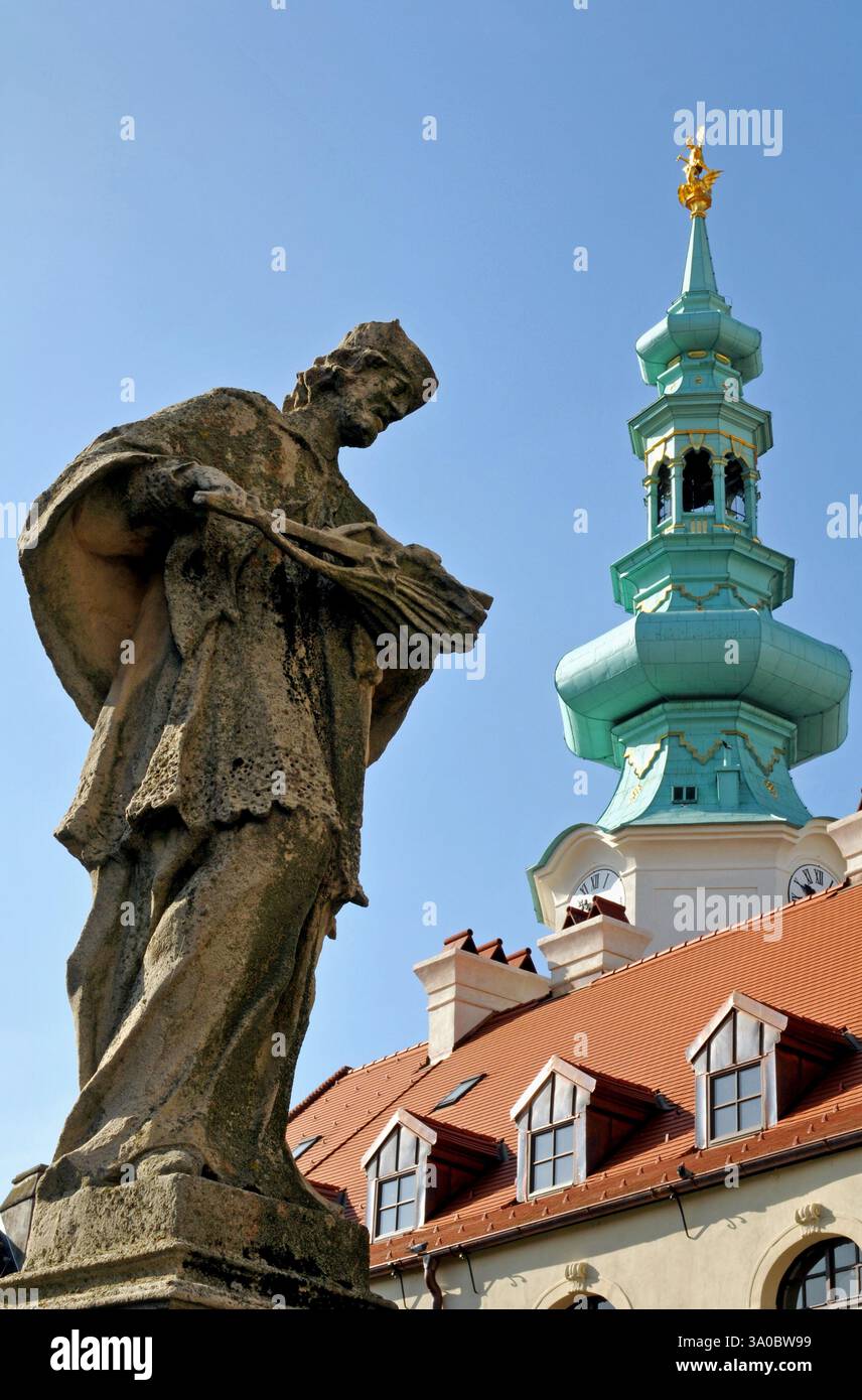 Una statua sorge su un ponte sotto la torre della porta di Michele nella storica città vecchia di Bratislava. Foto Stock