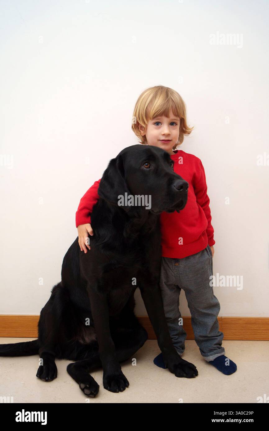 Bambino con cane labrador retriever nero Foto Stock