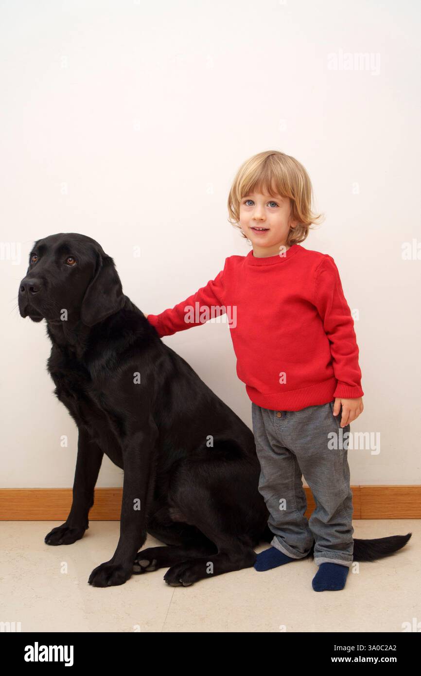 Bambino con cane labrador retriever nero Foto Stock