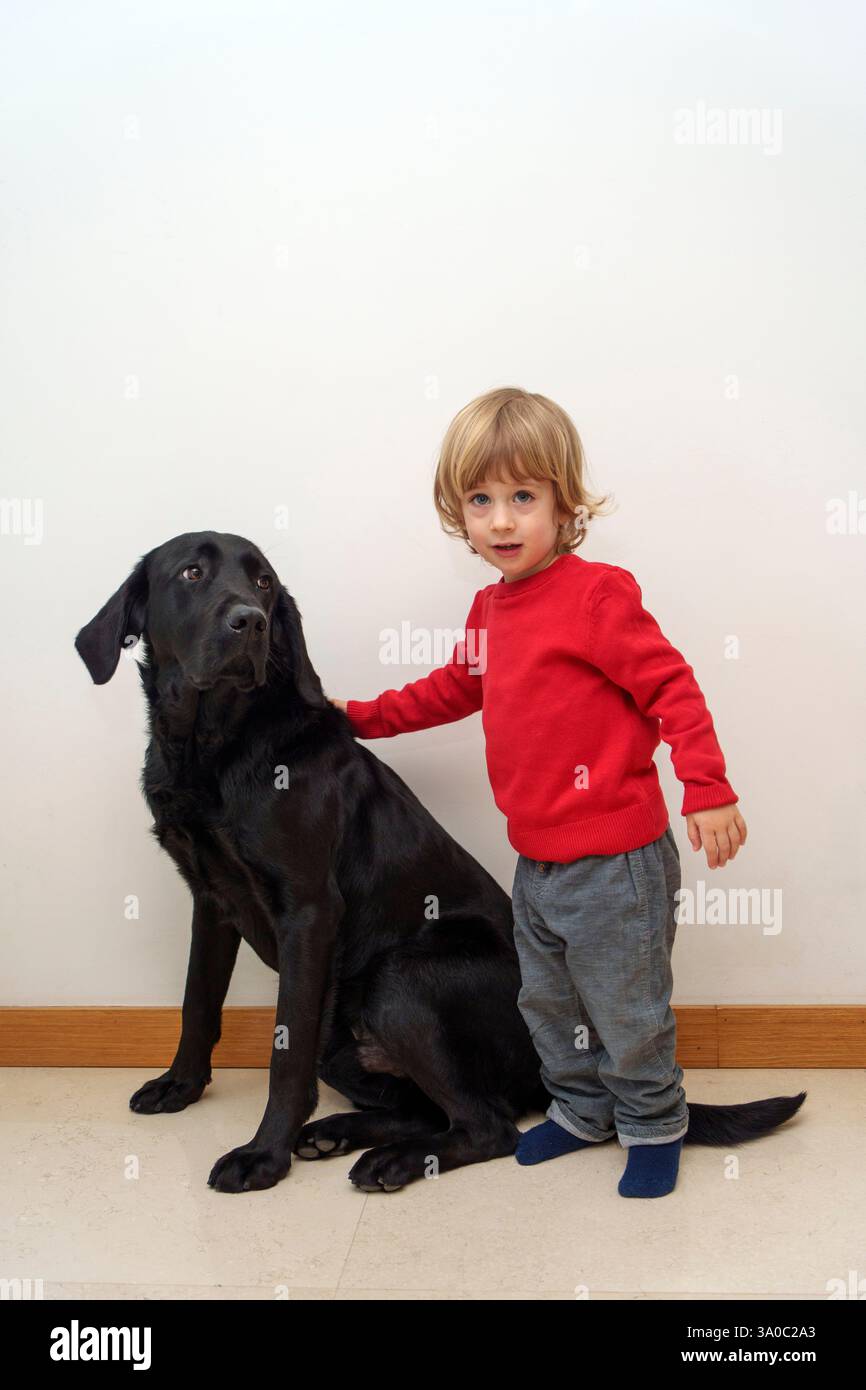 Bambino con cane labrador retriever nero Foto Stock