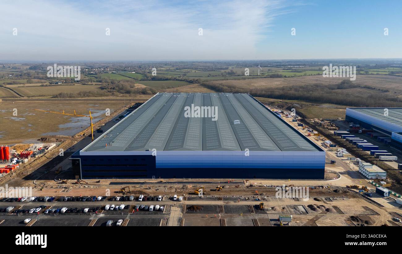 Vista aerea di un grande centro di distribuzione in costruzione, che mostra le sue vaste dimensioni e l'impatto sull'ambiente circostante Foto Stock