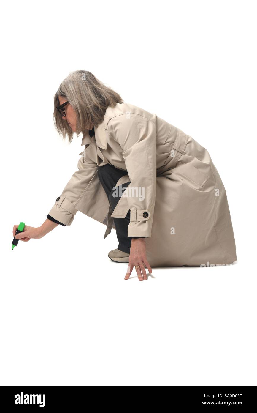 vista laterale di una donna accovacciata che disegna con un pennarello sul pavimento su sfondo bianco Foto Stock