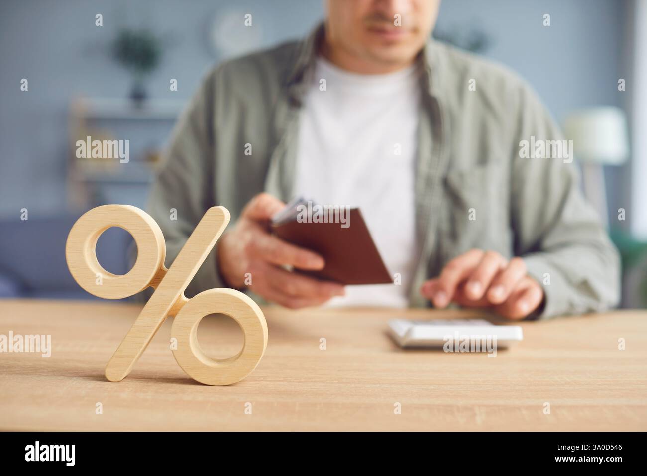 Primo piano del simbolo di percentuale e dell'uomo che conta il tasso di interesse bancario sulla calcolatrice. Foto Stock