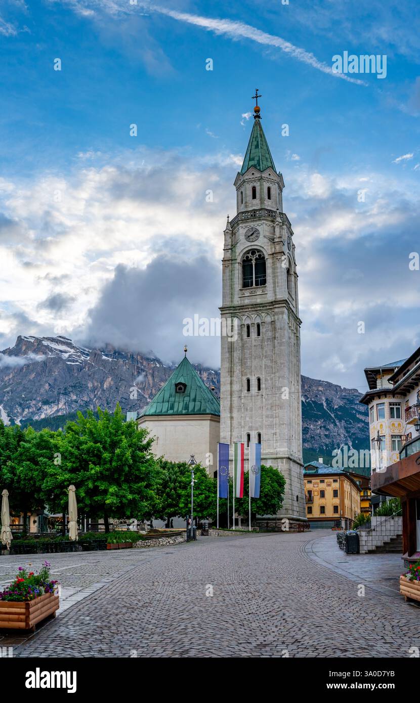 La Basilica minore dei Santi Filippo e Giacomo a Cortina d'Ampezzo al tramonto. Le nuvole più intense sullo sfondo creano un contrasto sorprendente con Foto Stock