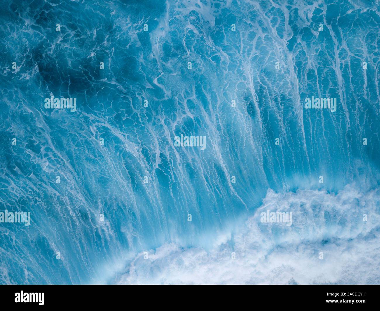 Vista aerea astratta di onde turbolente che si infrangono con sfumature blu e verdi delle acque tropicali dell'oceano Foto Stock