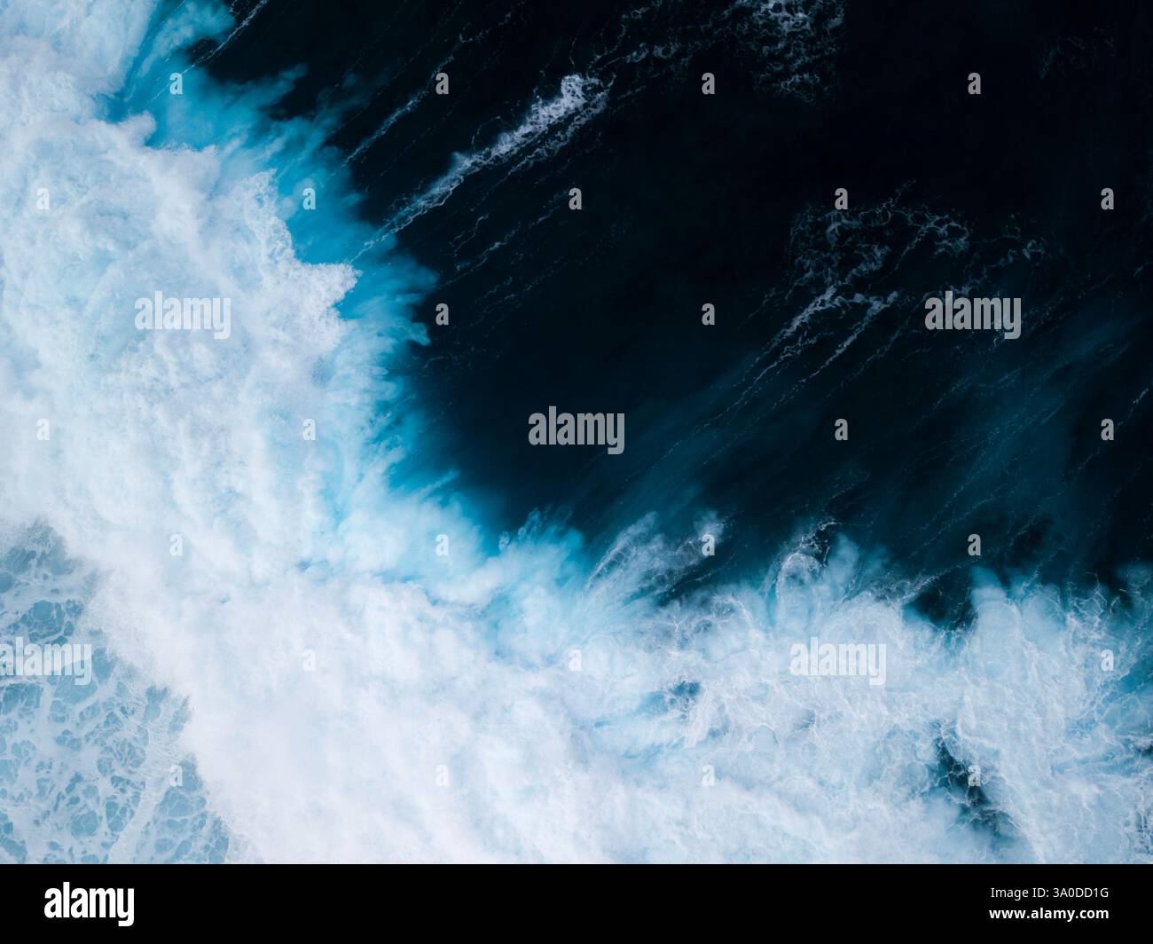 Vista aerea astratta di onde turbolente che si infrangono con sfumature blu e verdi delle acque tropicali dell'oceano Foto Stock