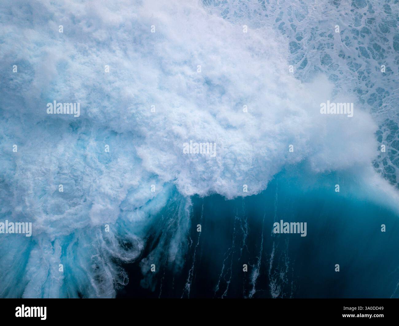 Vista aerea astratta di onde turbolente che si infrangono con sfumature blu e verdi delle acque tropicali dell'oceano Foto Stock